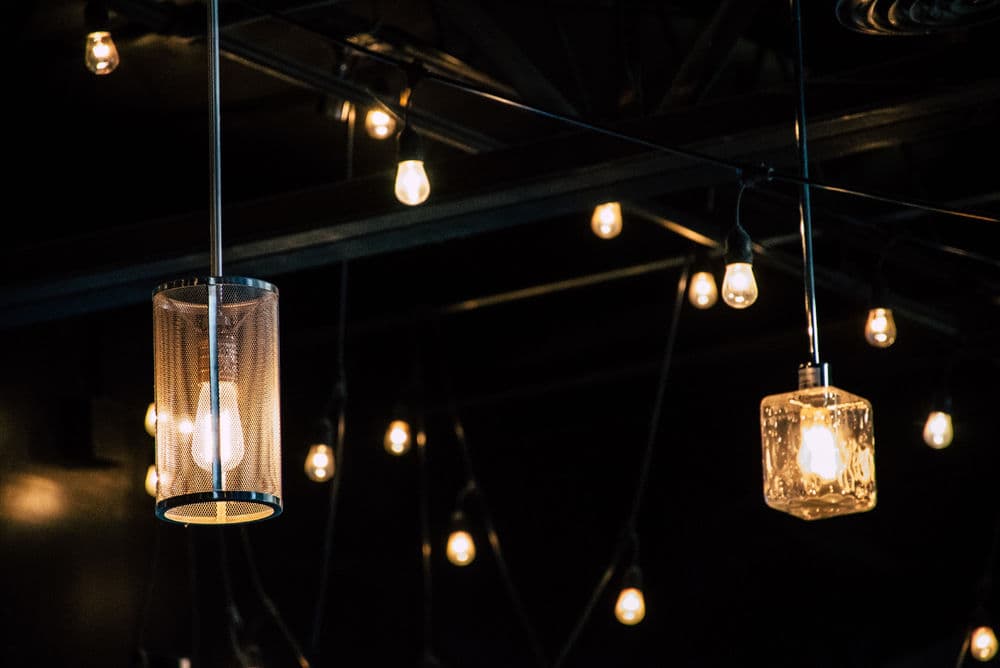 Stylish pendant lights and string bulbs illuminate a modern industrial ceiling.