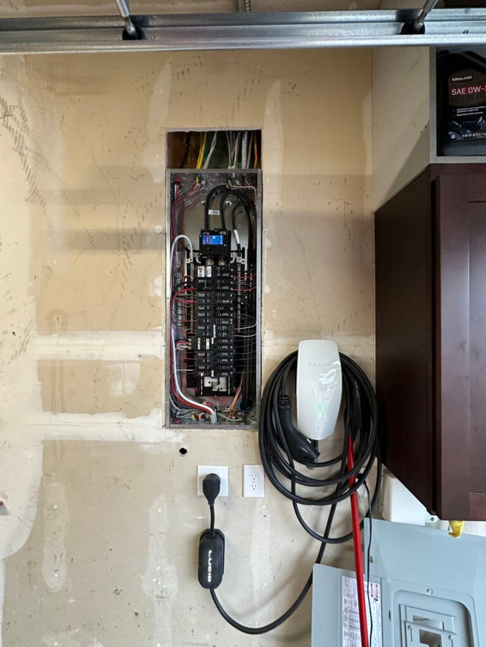 Electrical panel installation in a garage with charging station and organized wiring.