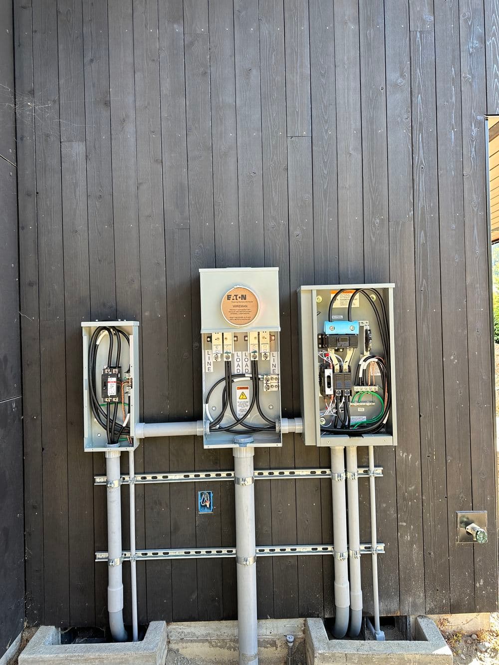 Electrical panel installation on a wooden wall with conduit and wiring details.