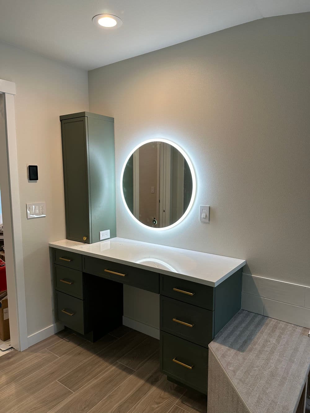 Modern green vanity with circular mirror and storage in well-lit room. Ideal for beauty routines.