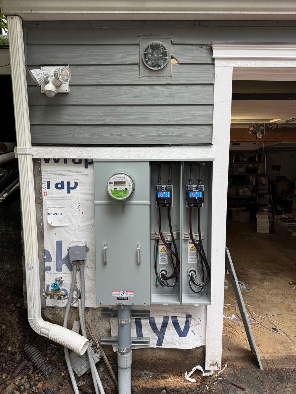 Electric meter and panel installed on a home's exterior, showcasing wiring and utility connections.